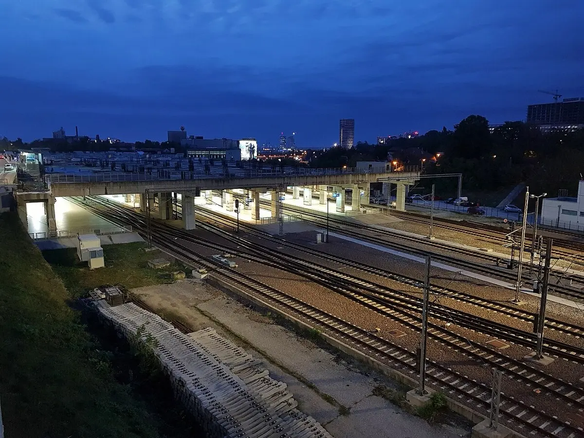 Platforms and tracks at Beograd Centar (Prokop) railway station at dusk, with the city skyline behind
