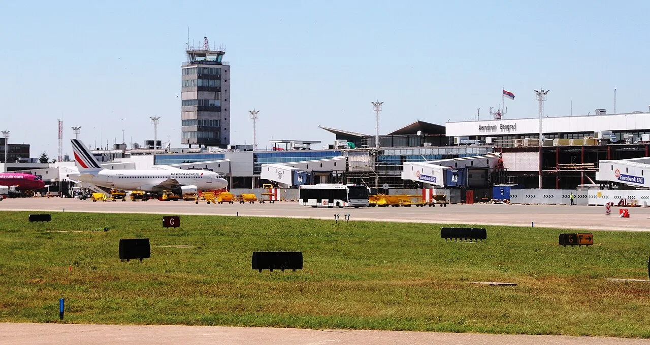 Aircraft parked at the terminal apron of Belgrade Nikola Tesla Airport, with the control tower behind