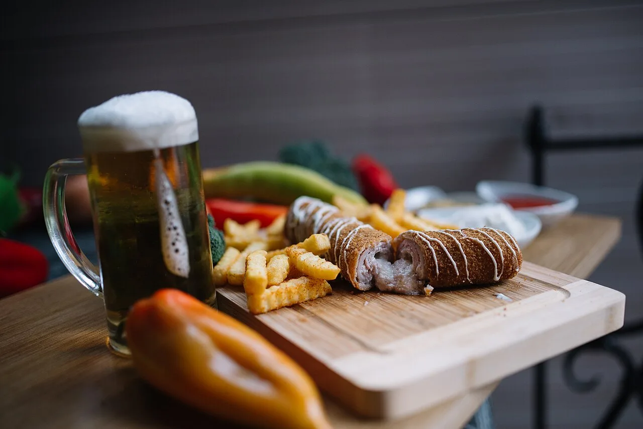 A glass of beer beside a plate of traditional Serbian grilled sausage in a restaurant