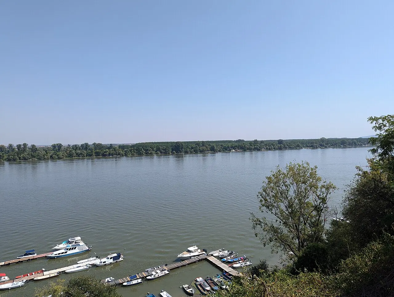 The Danube at Zemun with small boats moored along the quay and the far wooded bank beyond