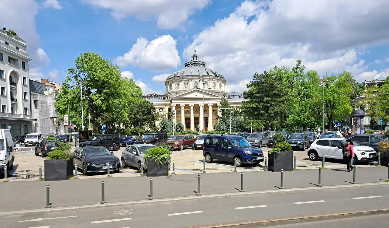 The domed Romanian Athenaeum concert hall in central Bucharest behind a tree-lined square