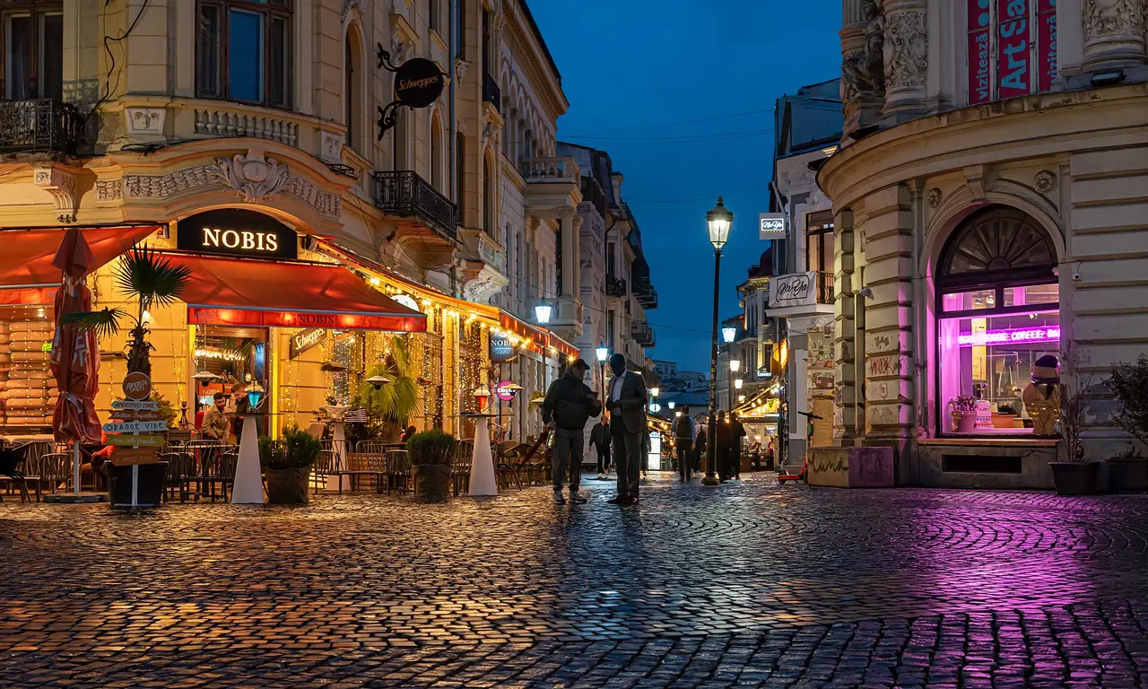 A cobbled Lipscani street in Bucharest Old Town glowing with bar lights at blue hour