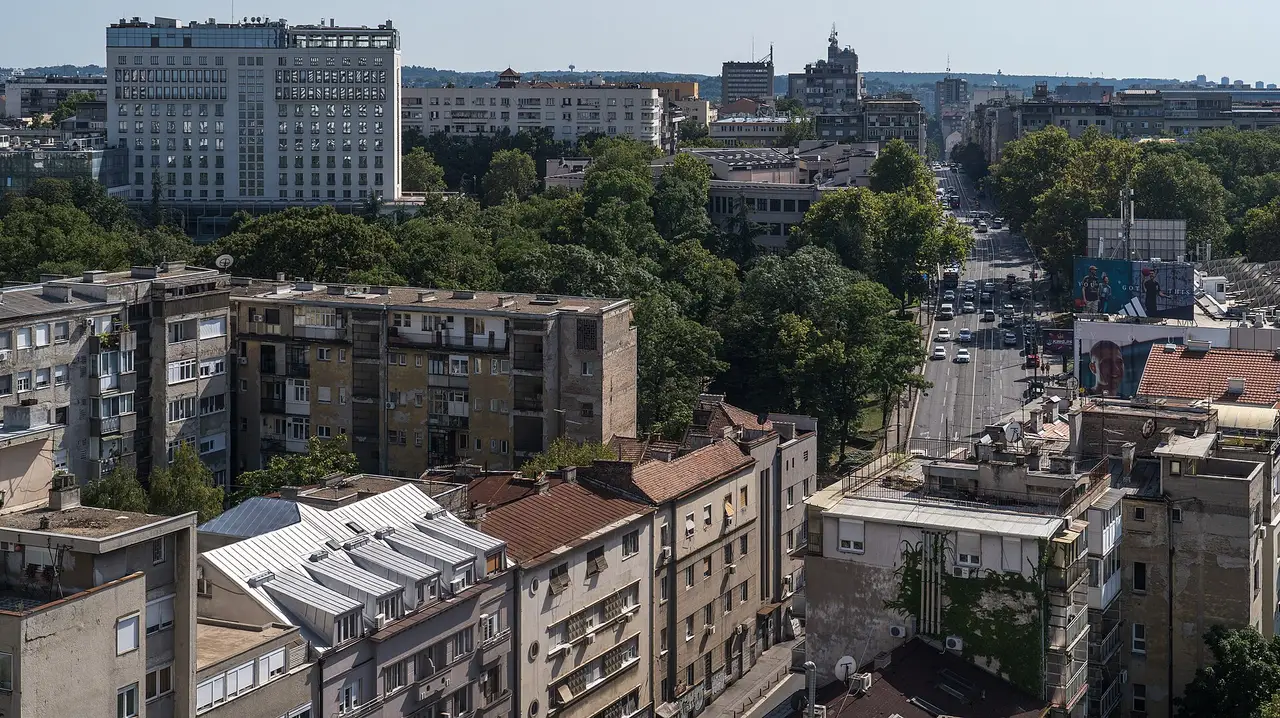 Belgrade rooftops and a tree-lined boulevard seen from above on a clear summer day
