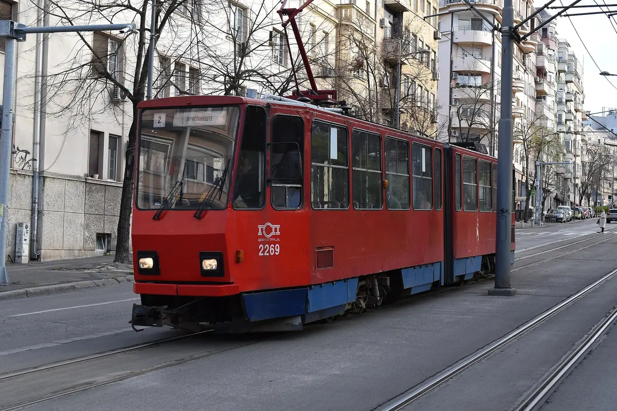 A red GSP Beograd tram on line 2 running along a Belgrade street