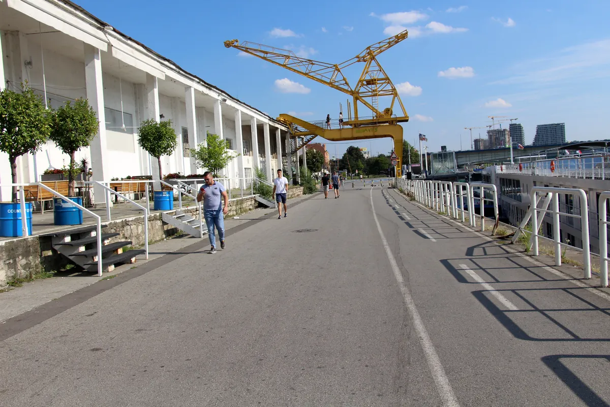 The Beton Hala waterfront in Belgrade, a converted dock warehouse with a yellow crane and a riverside walkway