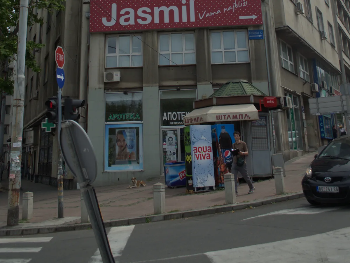 Street corner at Cetinjska in central Belgrade with a pharmacy, a newspaper kiosk and the street sign visible
