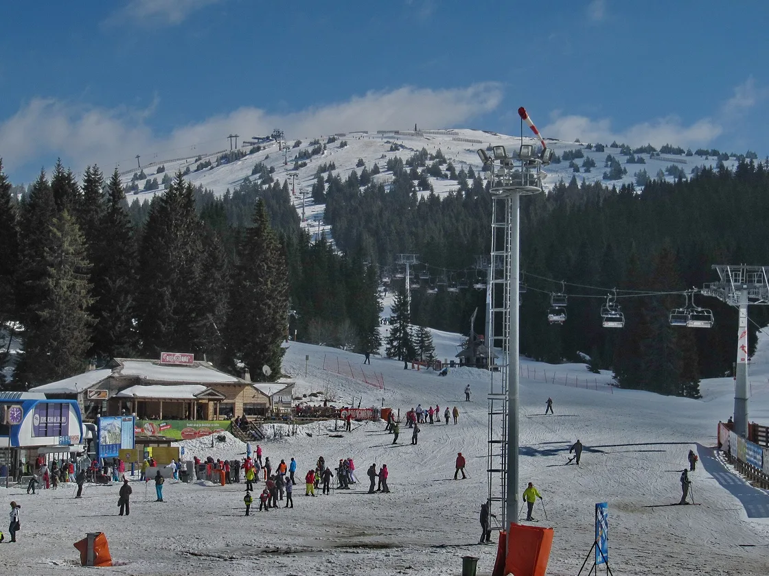 Skiers gathered at the foot of the slopes on Kopaonik with chairlifts running up the hill behind