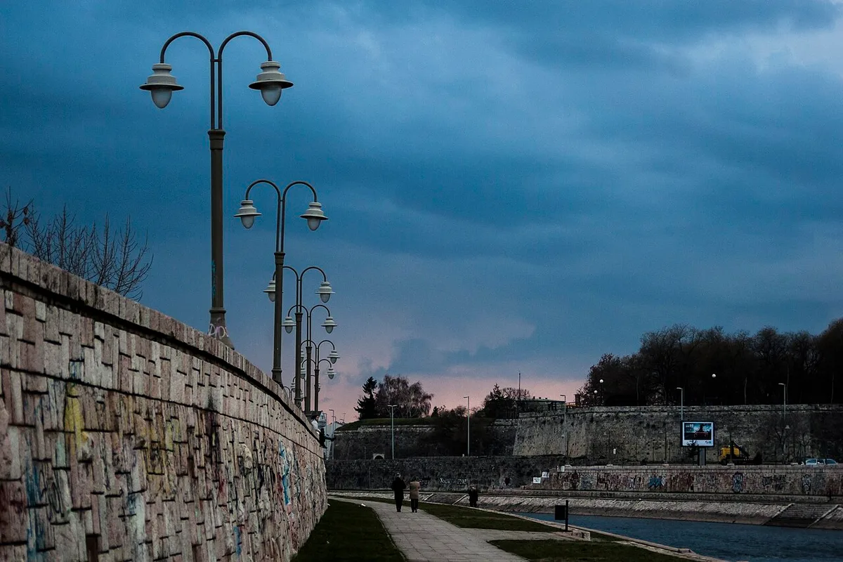 The riverside quay along the Nišava in Niš at dusk, with lamp posts and the fortress wall
