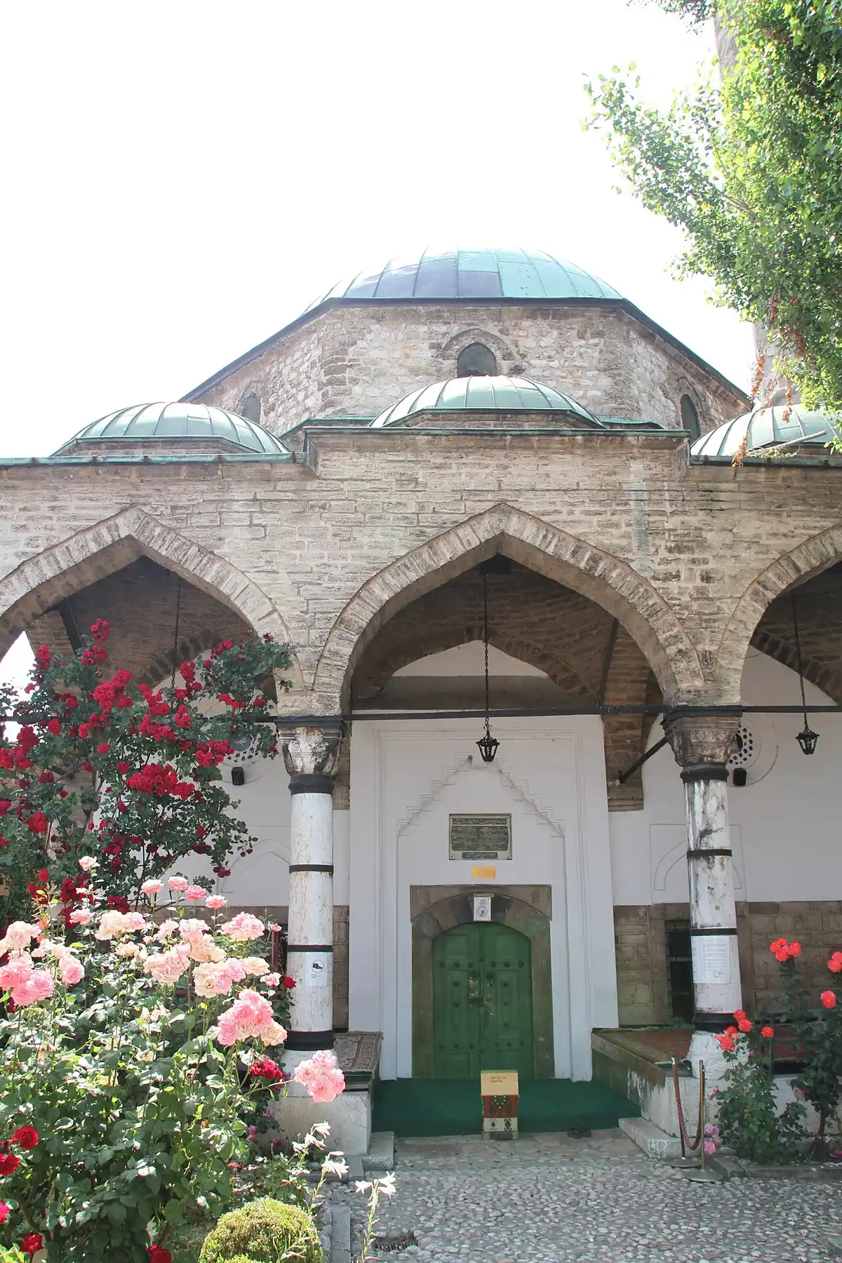A narrow cobbled street in Sarajevo old town lined with shops and an Ottoman mosque