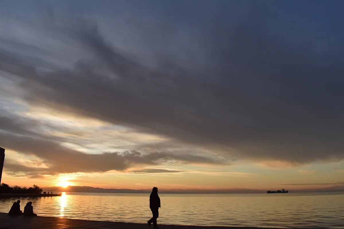 The Thessaloniki waterfront promenade along the Thermaic Gulf at sunset, with people strolling