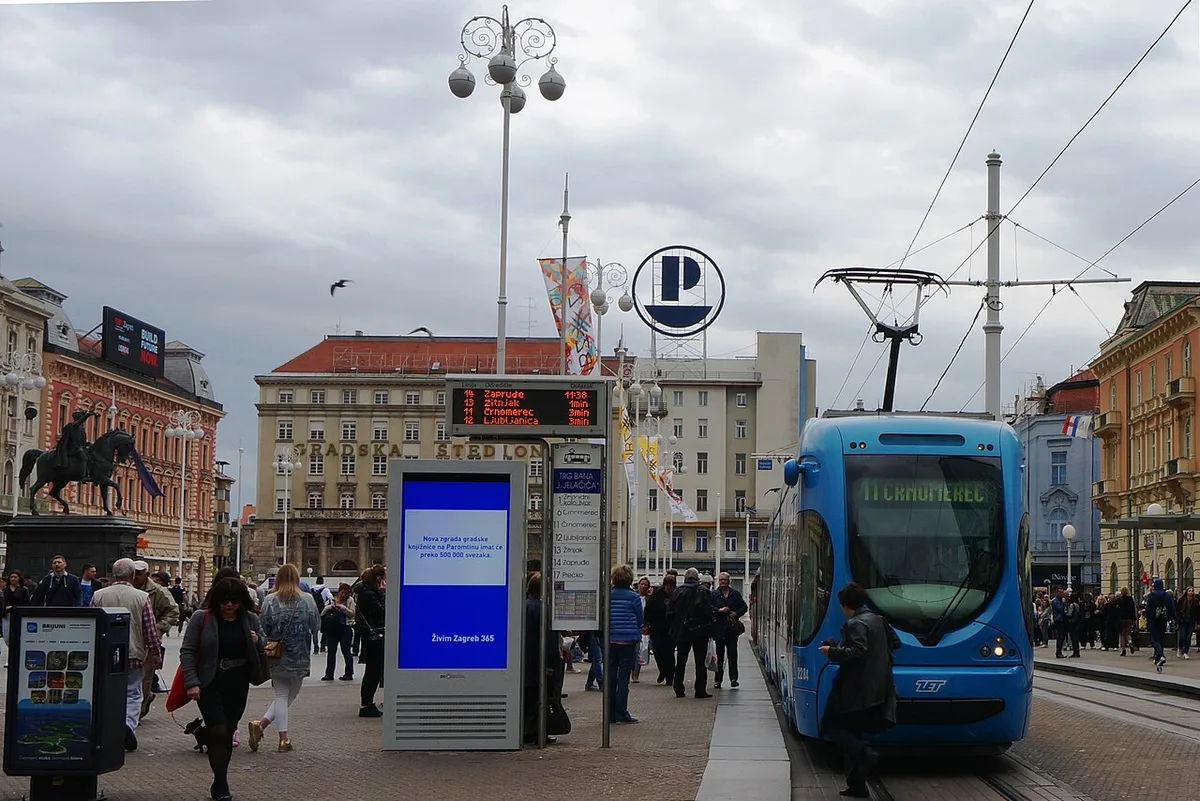 A blue tram crossing Ban Jelačić Square in central Zagreb on a sunny day