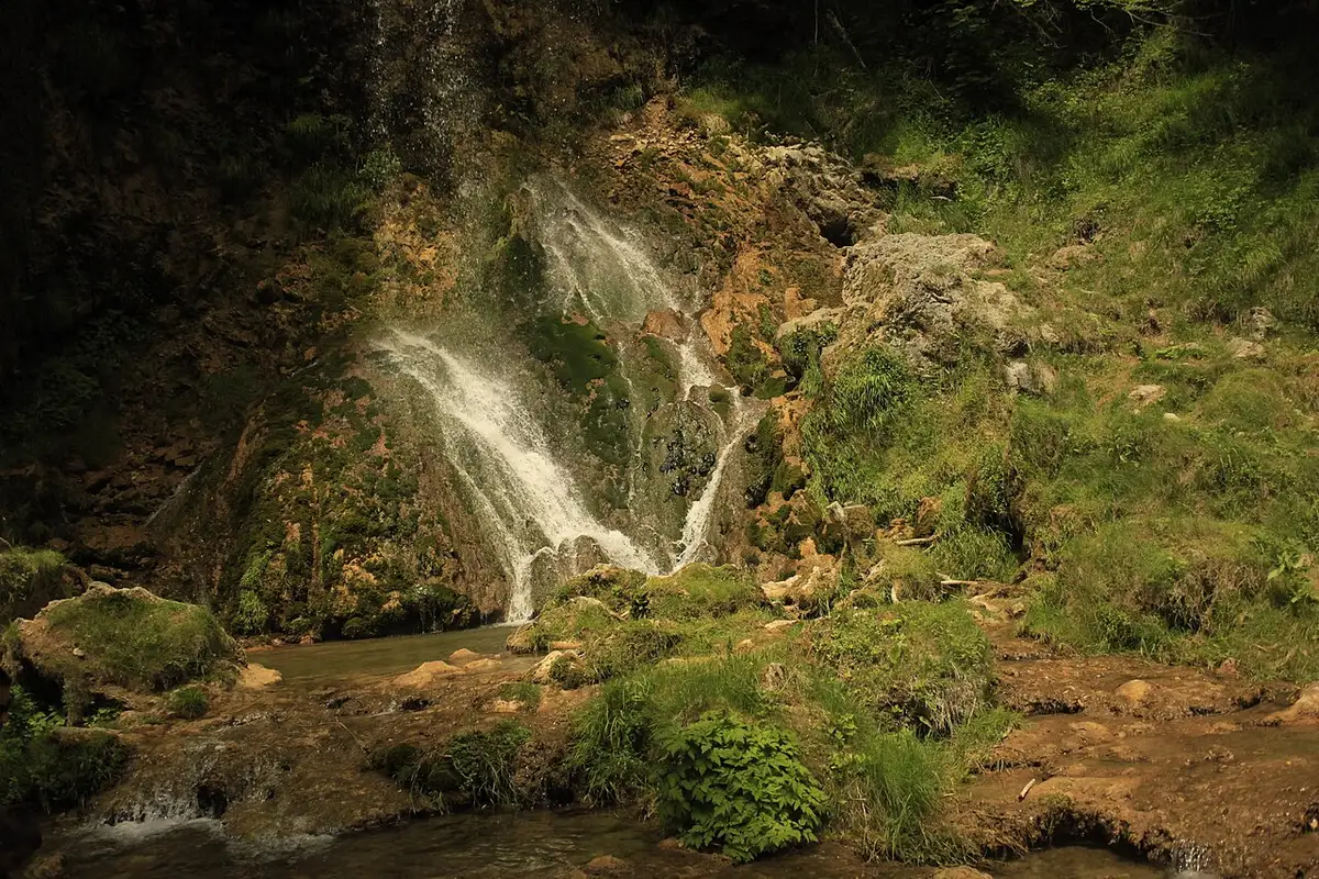 A waterfall cascading over mossy rocks in the wooded hills of the Zlatibor region