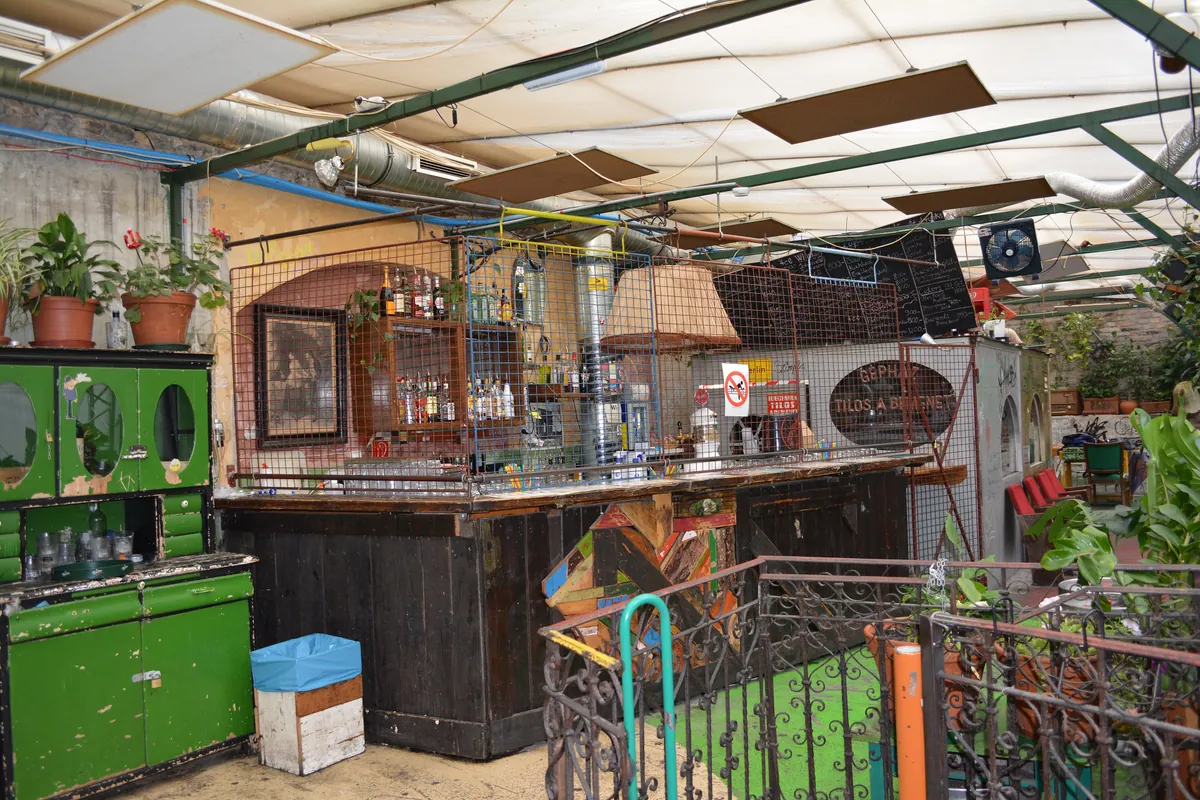 A bar counter inside Szimpla Kert in Budapest, built from salvaged wood and scrap under a translucent roof
