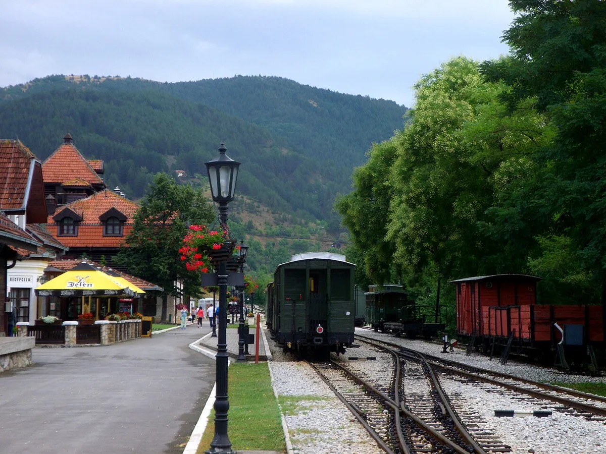 The narrow-gauge Šargan Eight heritage train at Mokra Gora station in western Serbia, forested mountains behind