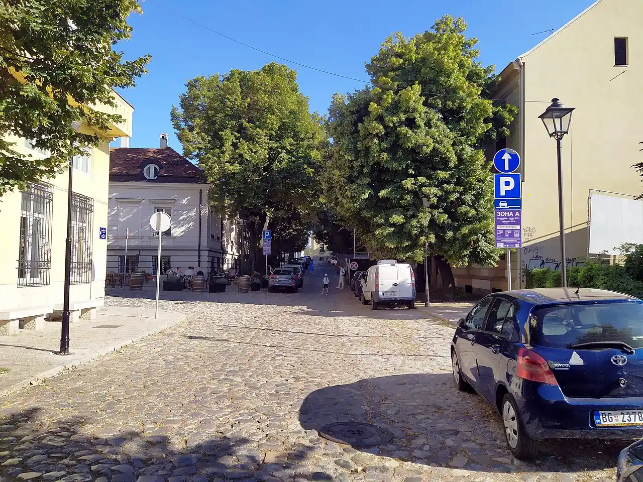 A quiet cobbled corner of Kosancicev Venac in Belgrade with cafe tables under trees