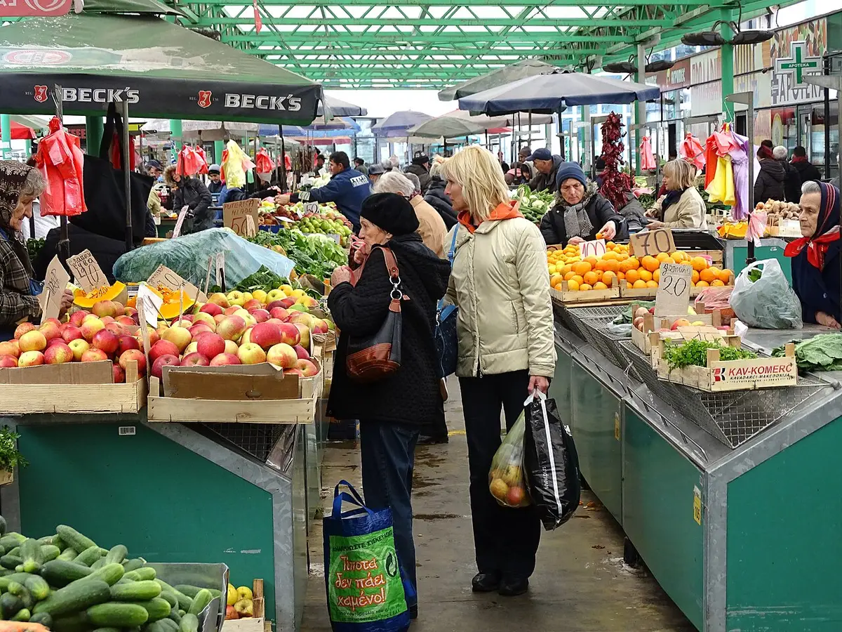 A vendor at a Belgrade produce market with crates of fresh fruit and vegetables