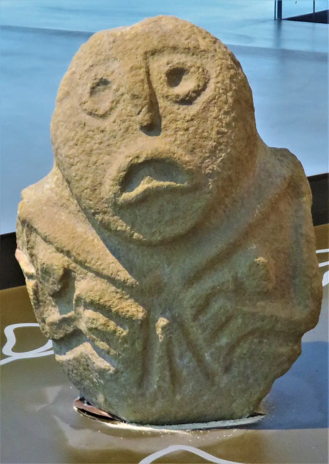 A carved sandstone head from Lepenski Vir with round eyes and a downturned fish-like mouth