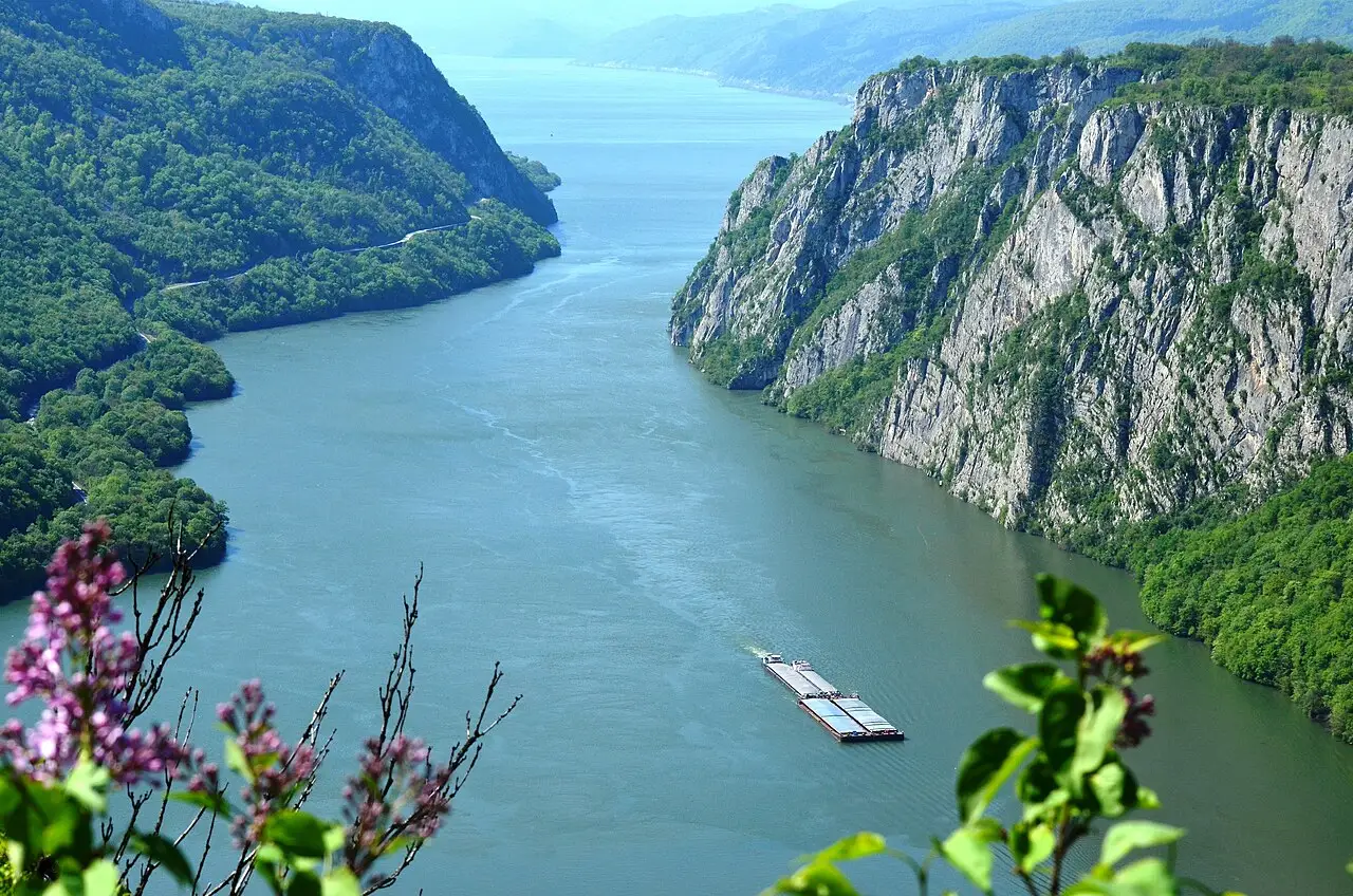 The Danube squeezed between limestone cliffs in the Kazan narrows seen from the Ploce viewpoint, a barge in midstream
