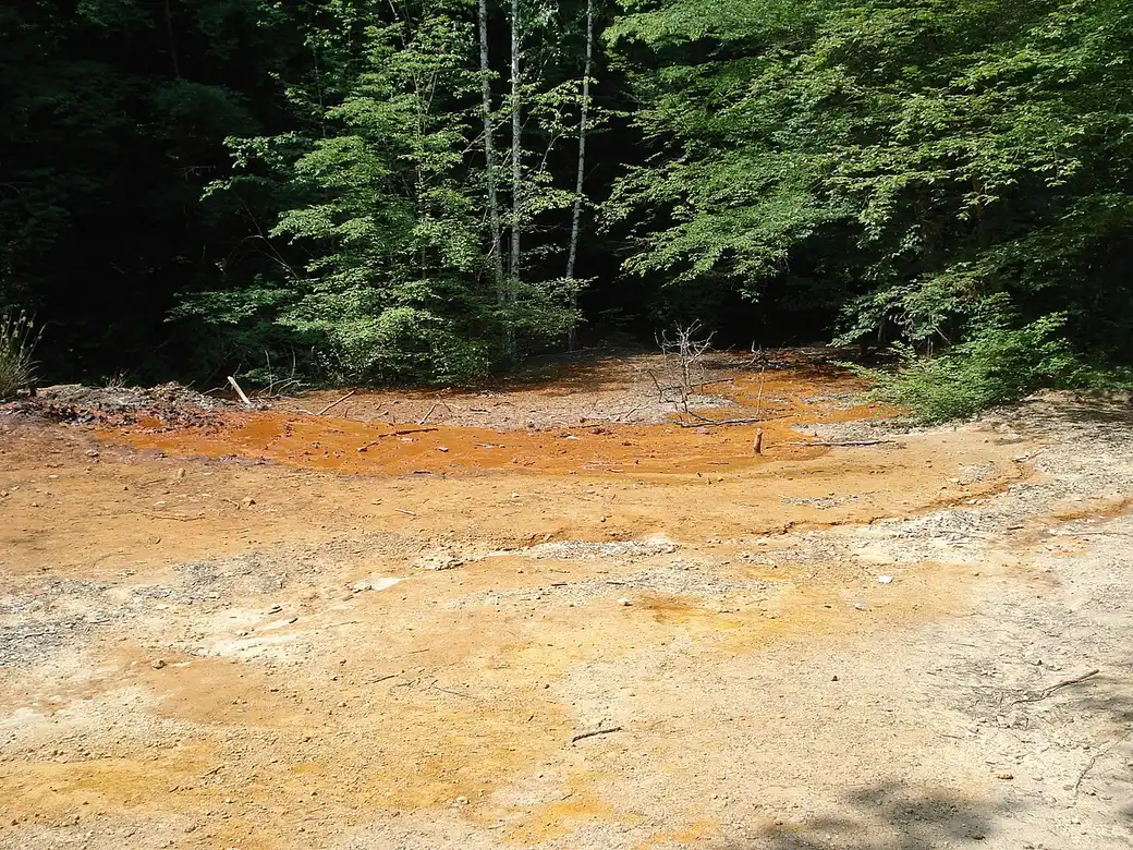The Crveno vrelo (Red Spring) at Đavolja Varoš, its iron-stained water and rust-red rock beside the path