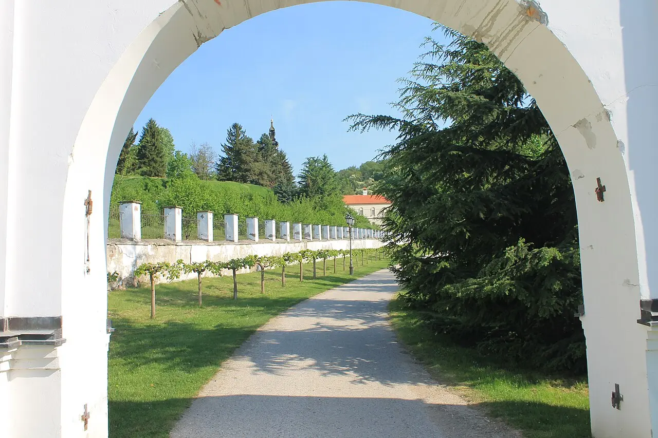 The baroque church and walls of Grgeteg monastery among trees on Fruska Gora