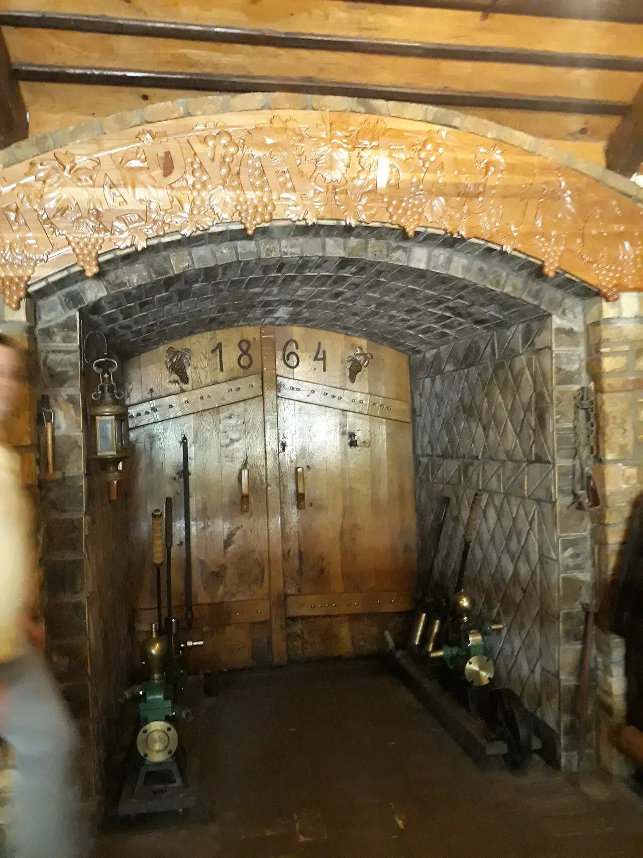 Carved 1864 doorway and green pumps at the Bajilo cellar entrance in Sremski Karlovci