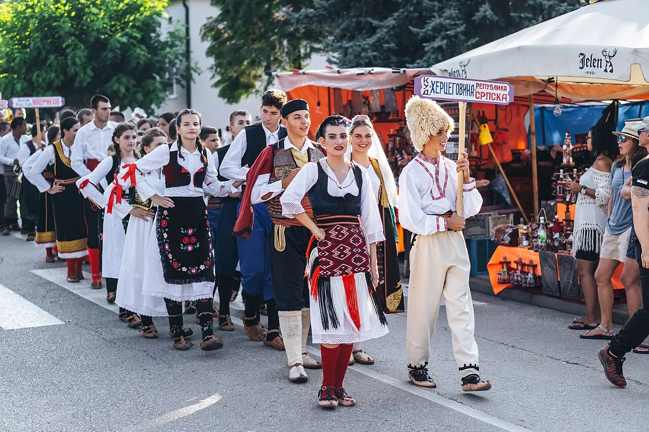 A line of young dancers in embroidered Serbian folk costume parading through Guča during the festival defile