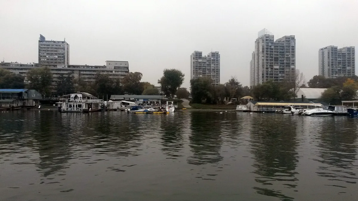 The residential tower blocks of New Belgrade seen across the Sava river, with houseboats moored at the bank