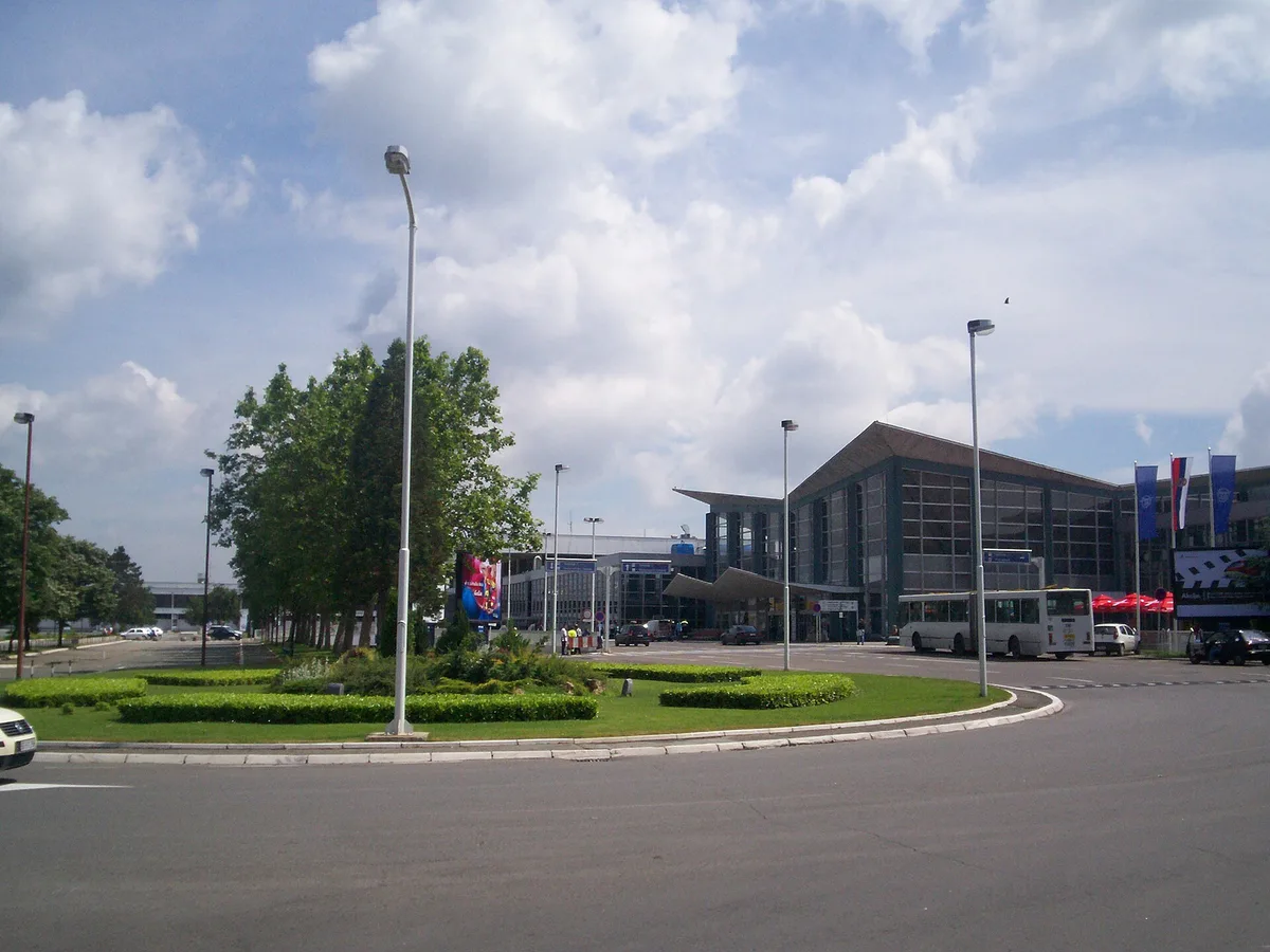 The terminal building and forecourt of Belgrade Nikola Tesla Airport, with a bus and taxis outside