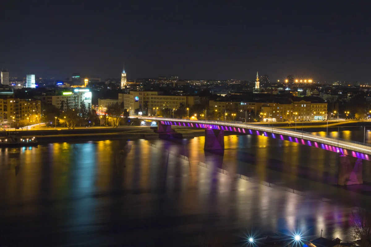 Novi Sad at night seen from Petrovaradin Fortress, the illuminated Varadin bridge reflected in the Danube