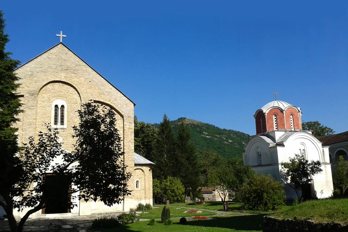 The medieval churches of Studenica Monastery, one with a red dome, in a green mountain valley in south-west Serbia