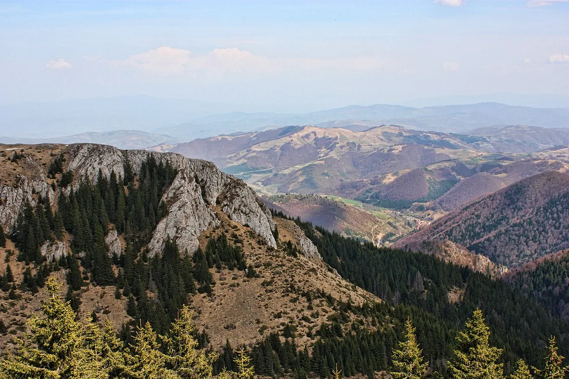 White rocky crags and spruce forest falling away to rolling wooded hills inside Kopaonik National Park