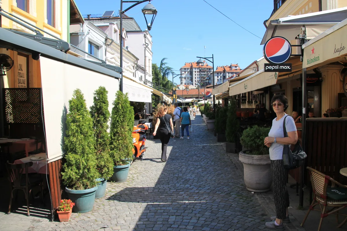 The cobbled Tinkers Alley (Kazandžijsko sokače) in Niš lined with café awnings, tables and strollers on a sunny day