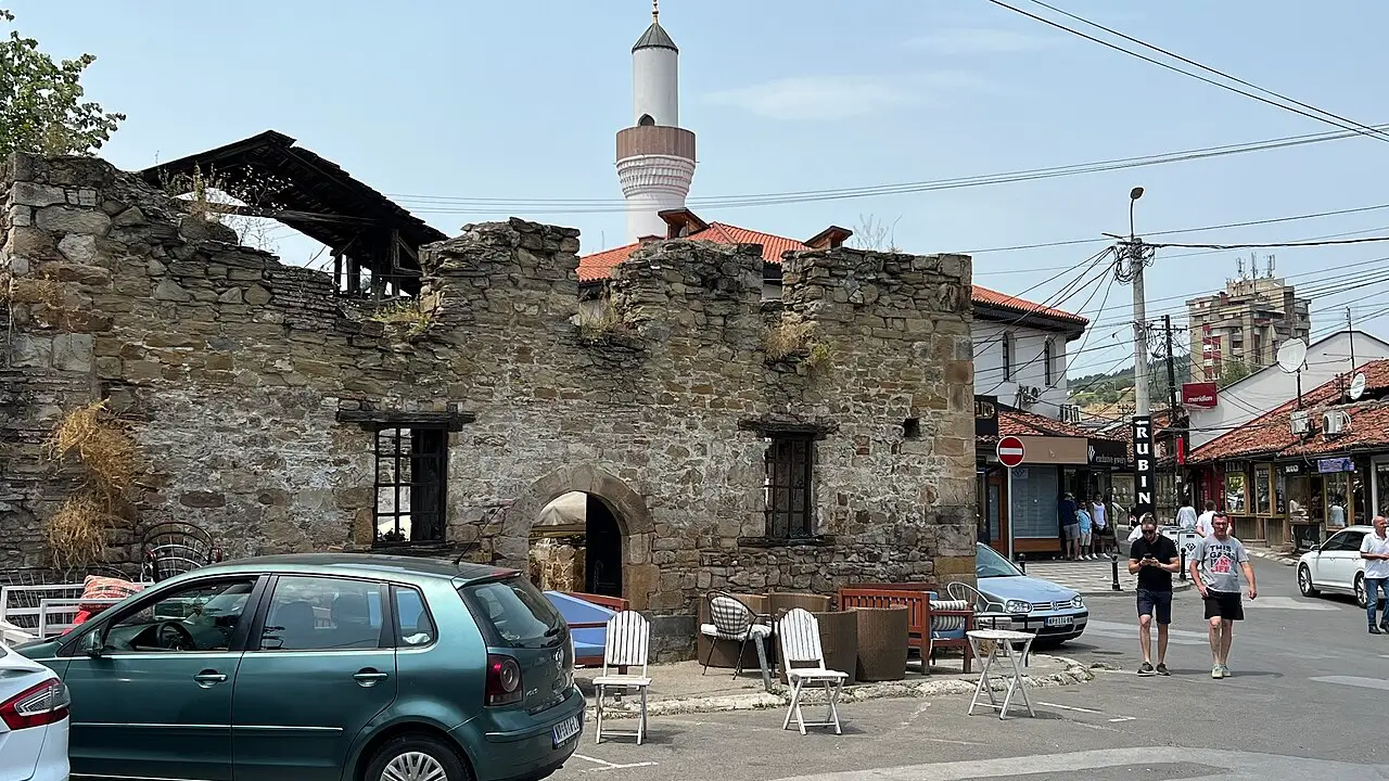 The roofless stone walls of the 15th-century Turkish bath in Novi Pazar with a minaret behind