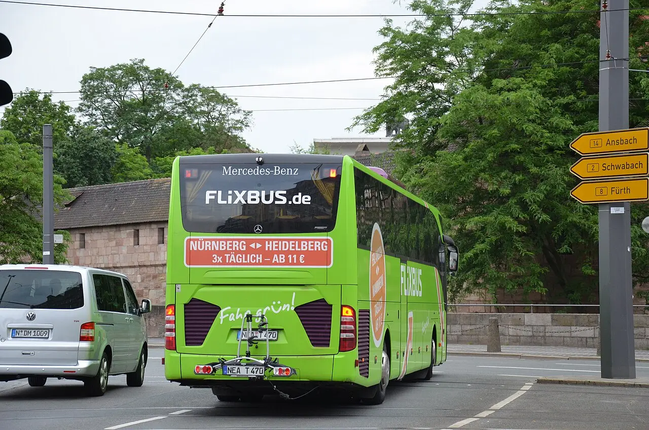 A green FlixBus Mercedes-Benz Tourismo coach parked at a terminal bay