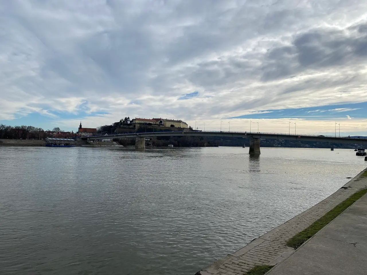 The Danube in Novi Sad with a road bridge and Petrovaradin Fortress on the far bank seen from the quay