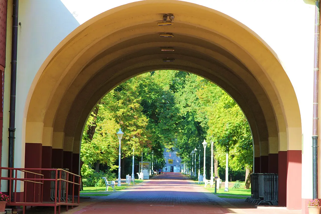 The archway under the Grand Terrace at Palic framing the tree-lined promenade beyond