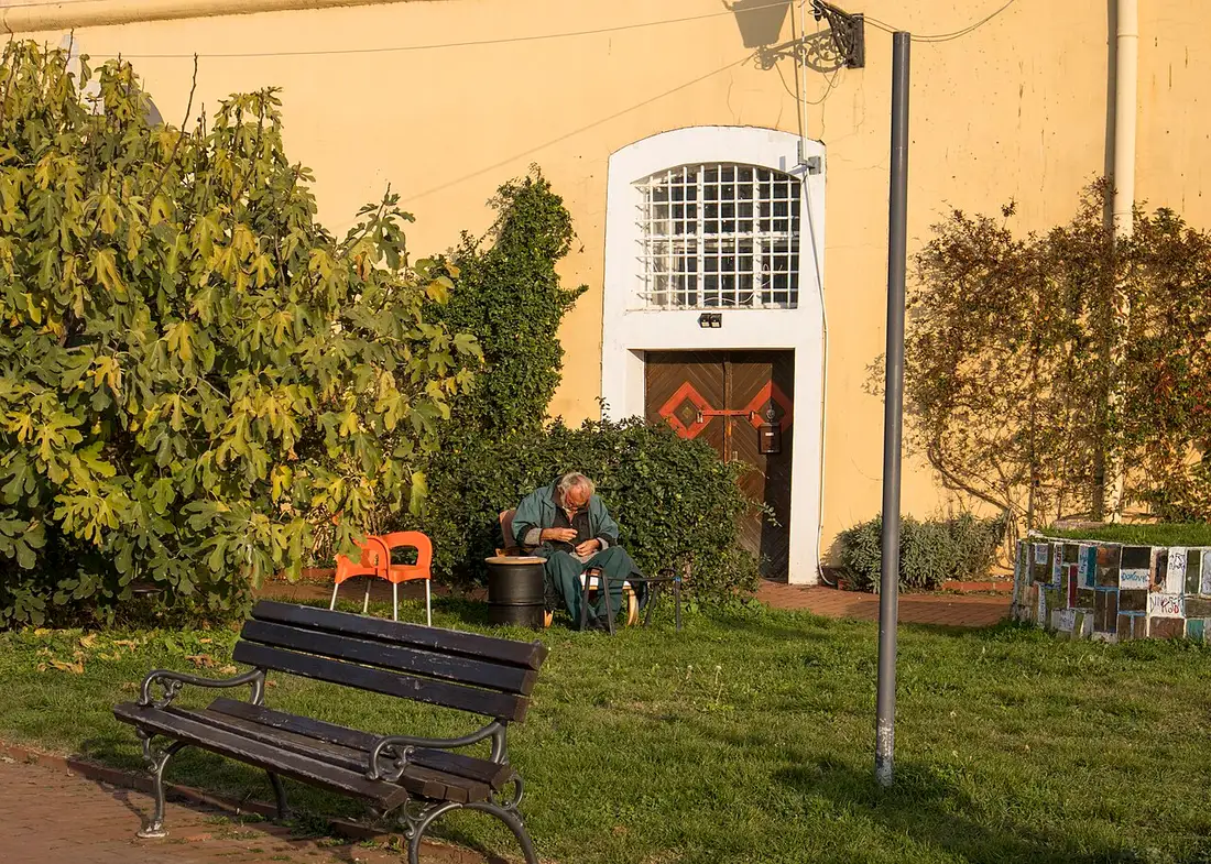 An artist sitting and working in golden light outside a studio door built into the wall of Petrovaradin Fortress