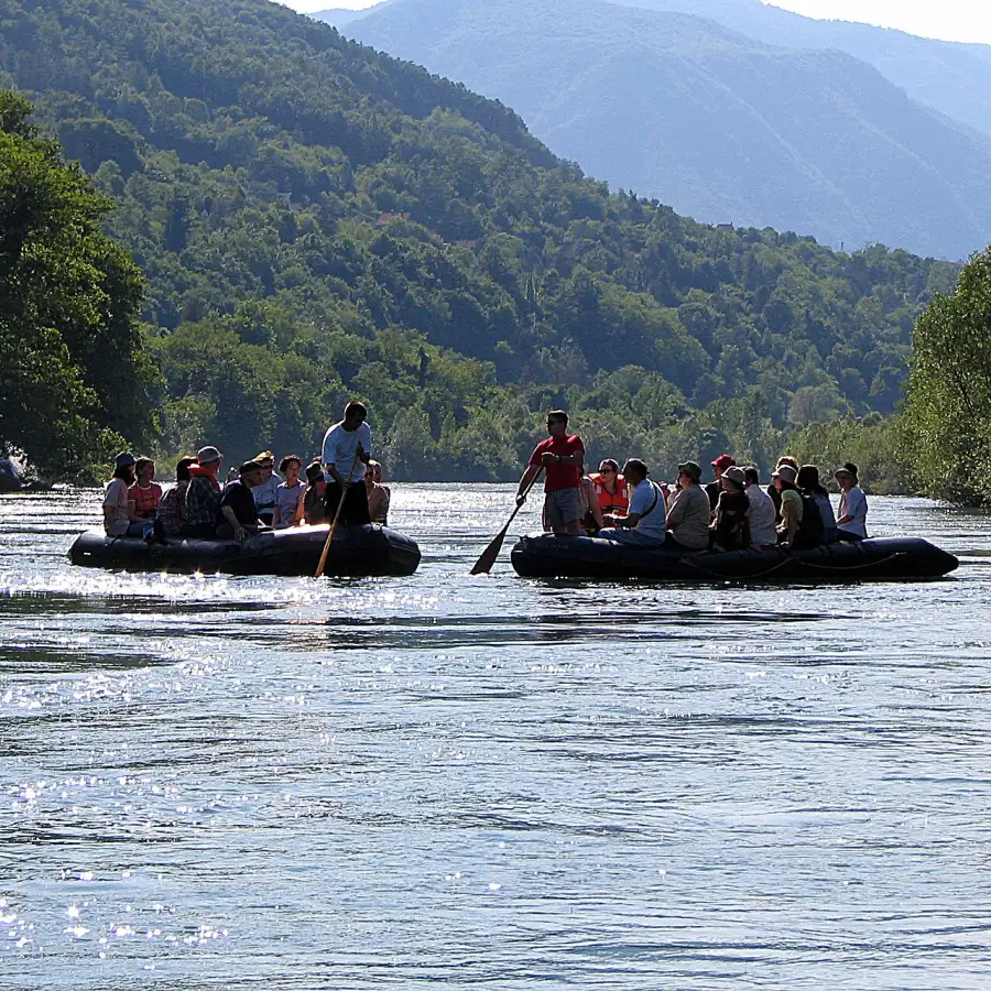 Rafting boats on the green Drina river with forested hills rising behind