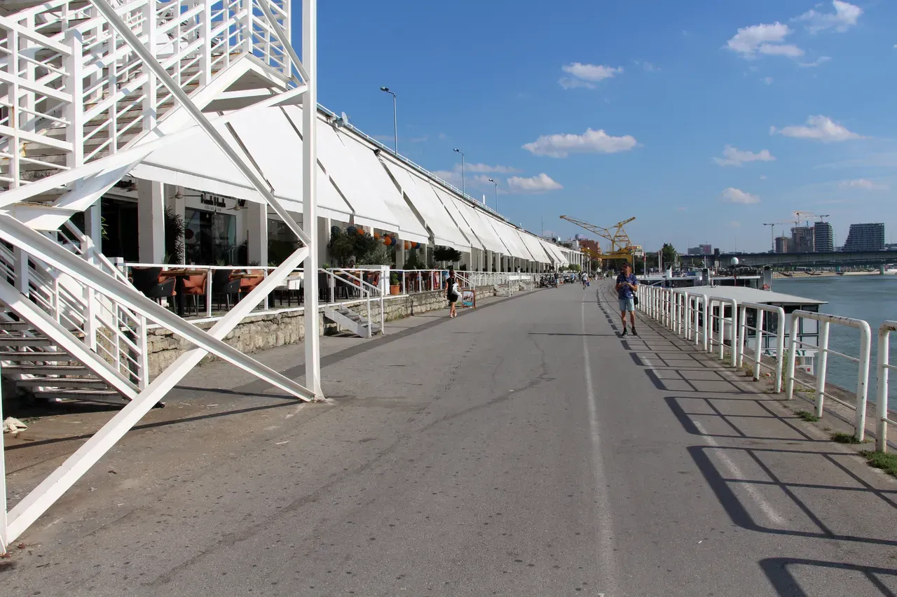 Restaurant terraces with white awnings along the Beton Hala riverside promenade in Savamala