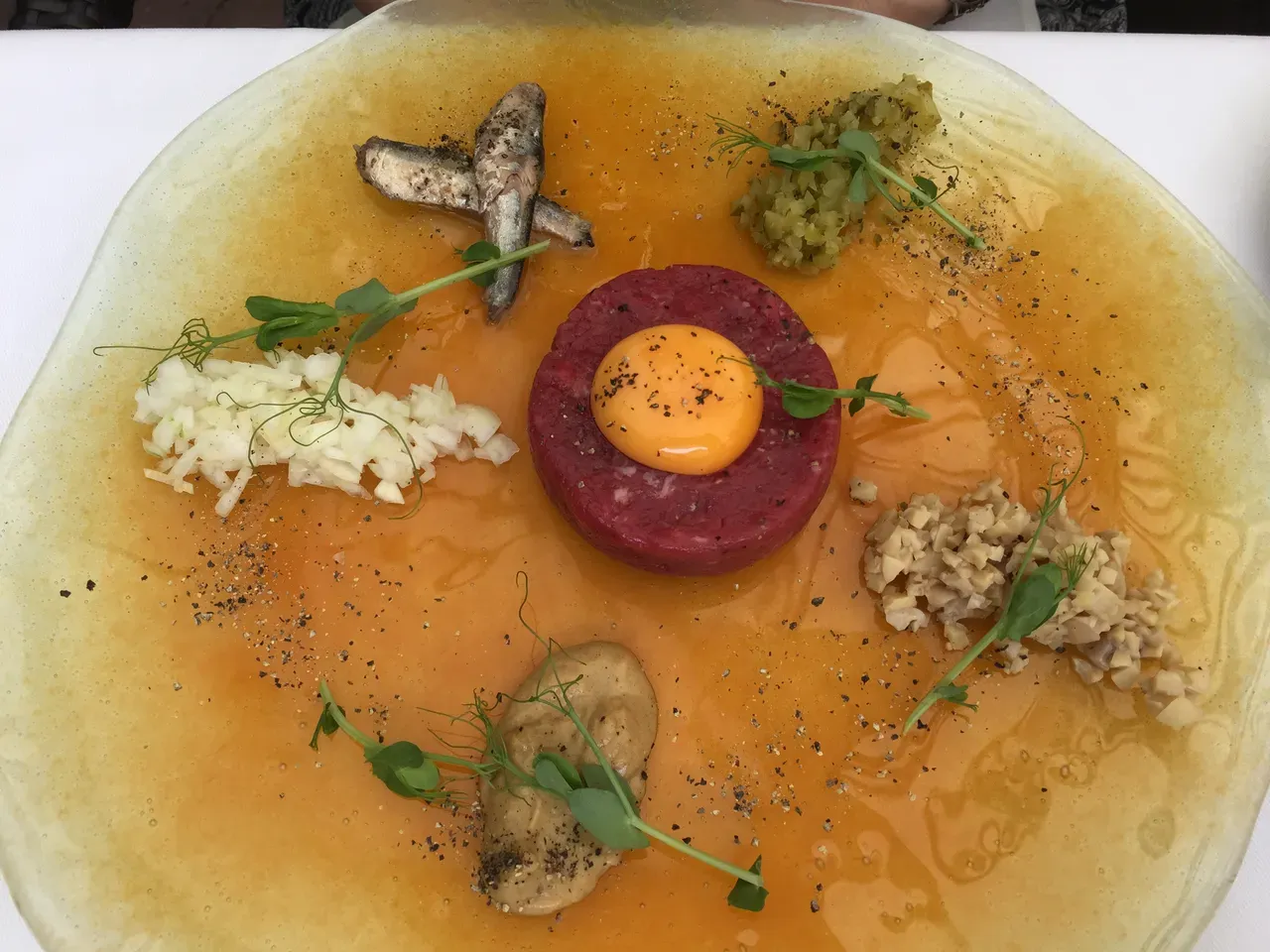 An elegantly plated steak tartare with egg yolk and garnishes at a fine-dining restaurant