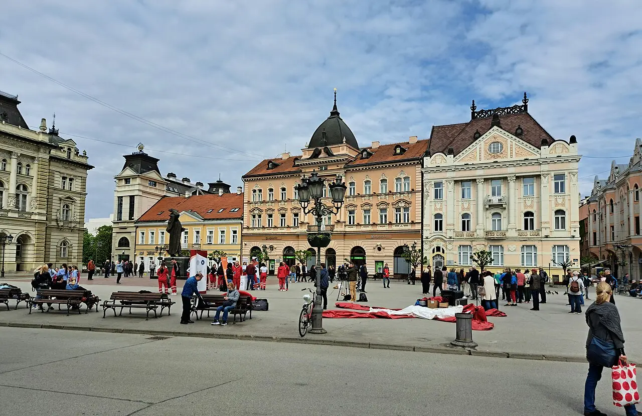 Freedom Square in Novi Sad framed by pastel neo-Renaissance buildings and a green-domed palace under a bright sky