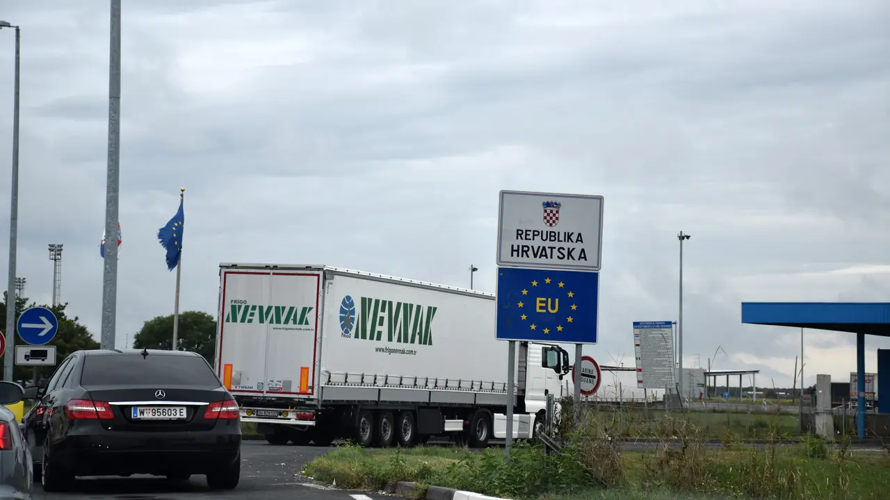 The Republika Hrvatska and EU boundary signs beside a lorry and waiting cars at the Bajakovo border crossing