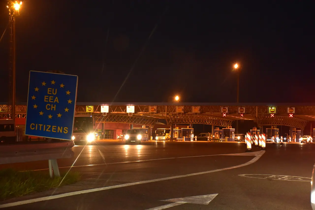 A blue EU EEA CH CITIZENS lane sign lit up at night in front of the booths at the Bajakovo crossing