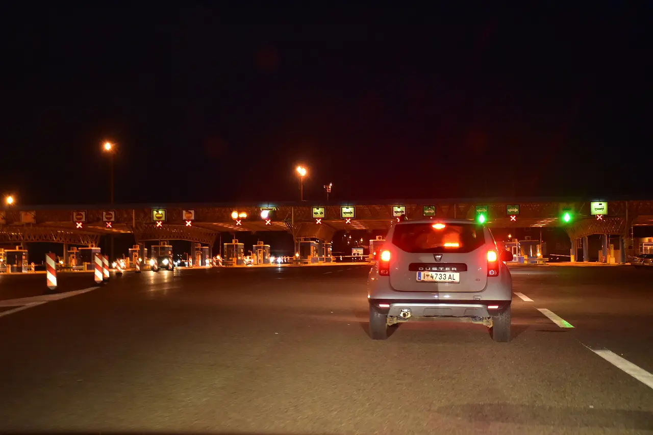 A car waiting at night in front of the Bajakovo booths, with red crosses over the closed lanes and two green arrows