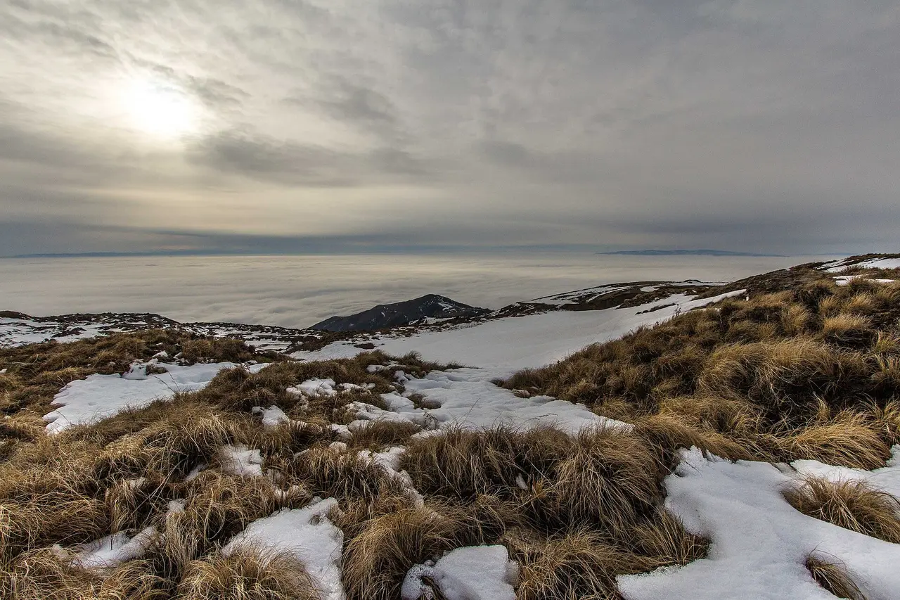 A Serbian mountain ridge in patchy snow standing above a flat white sheet of cloud filling the valleys below