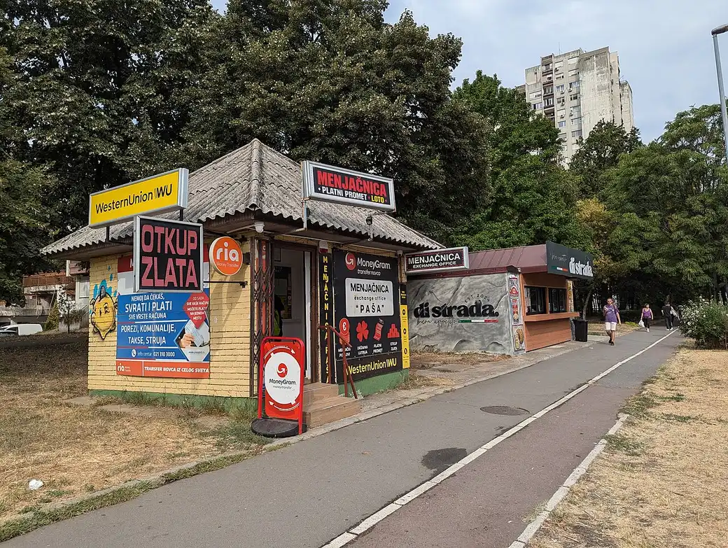 A small currency exchange kiosk with a posted buy and sell rates board on a Belgrade street