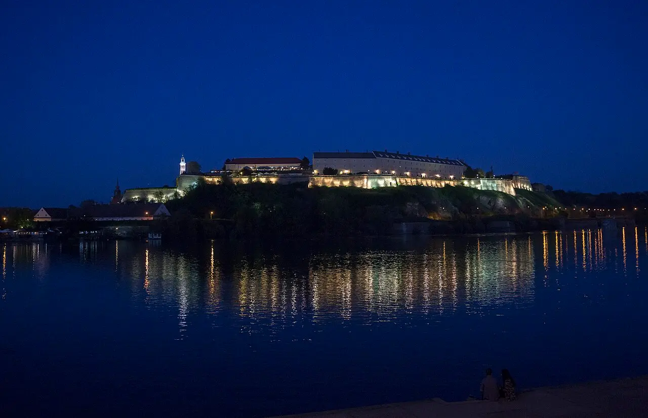 Petrovaradin Fortress in Novi Sad lit up above the Danube at night, its lights reflected in the water, EXIT festivals former home