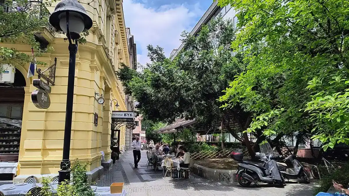 A sunny summer street of old Belgrade with cafe awnings and pedestrians
