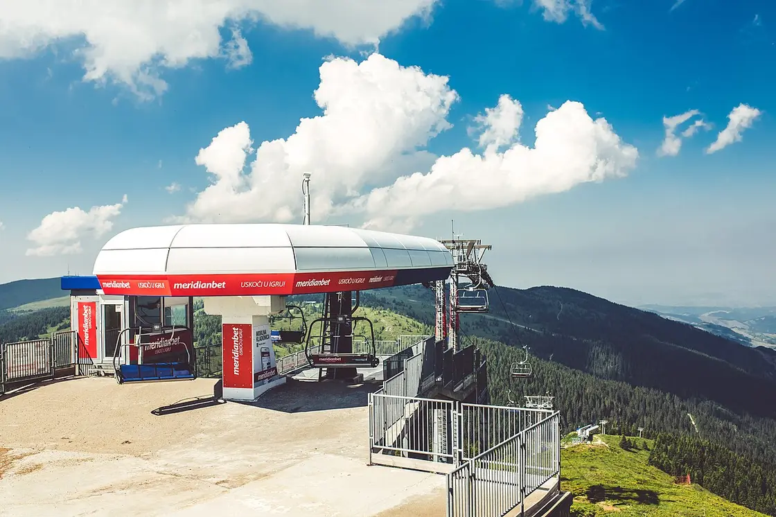 A ski lift climbing a green Kopaonik ridge under a wide sky