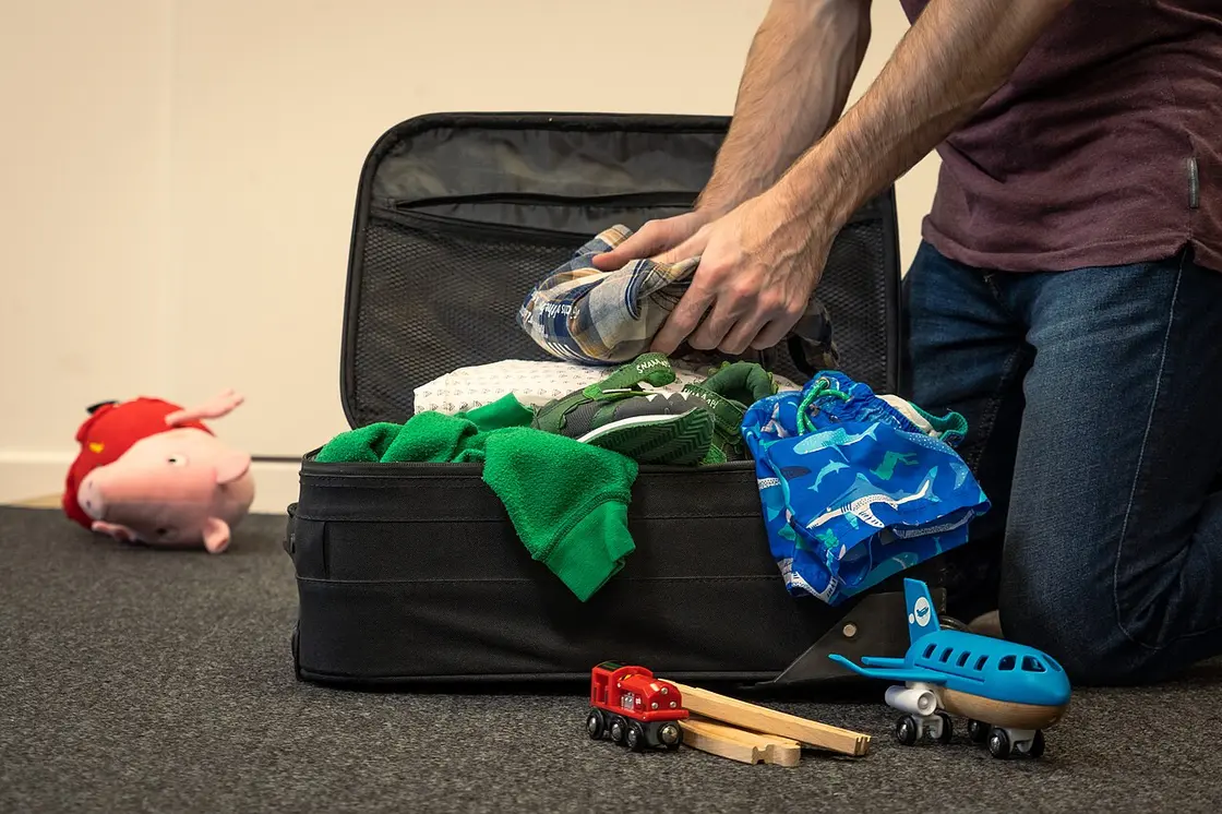 An open suitcase being packed with folded clothes for a holiday